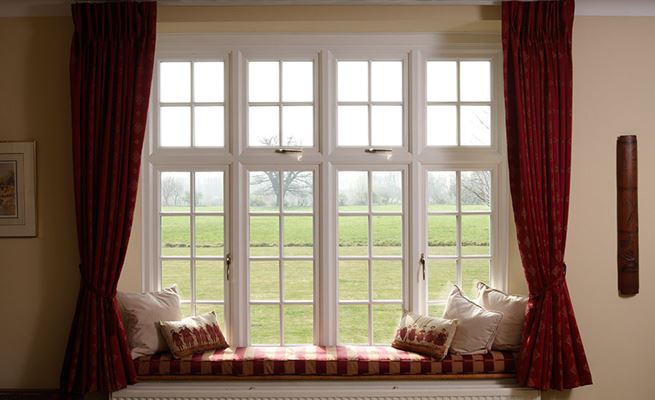Large White timber casement window with cottage bars finished with a window seat from the Anglian double glazing range