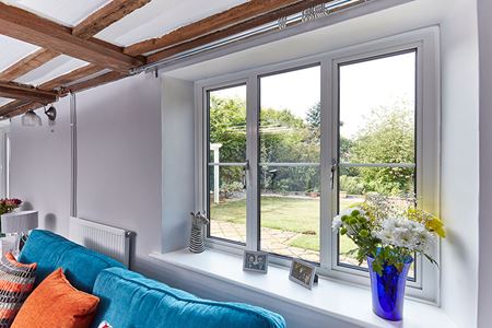 Close up of White aluminium casement window first floor opening onto garden from the Anglian aluminium windows range