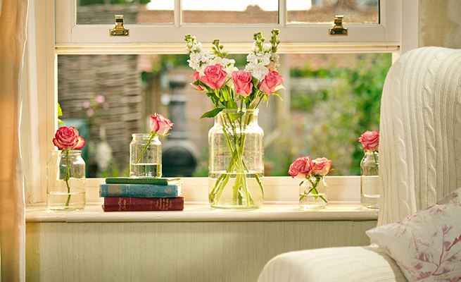 Close up of open White wooden sash window with gold window furniture and flowers from Anglian Home Improvements