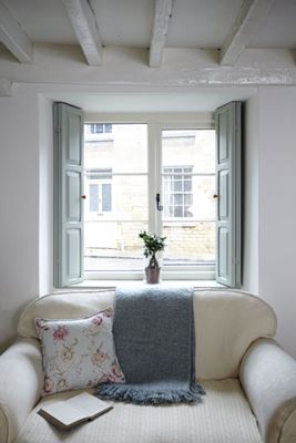 White wooden cottage style living room window with decorative monkeytail window handle and shutters from Anglian Home Improvements